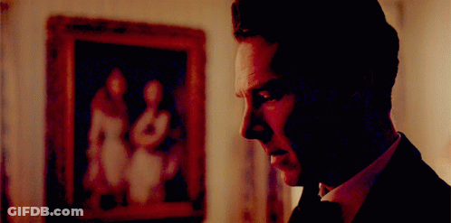 A Man In A Suit And Tie Is Looking At A Framed Picture GIF