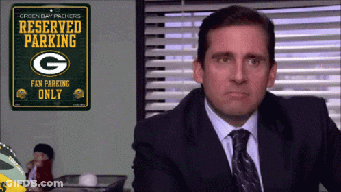 A Man In A Suit And Tie Is Looking At A Green Bay Packers Reserved Parking Sign GIF