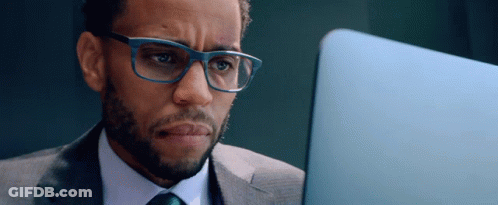 A Man In A Suit And Tie Is Looking At A Laptop GIF