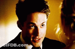 A Man In A Suit And Tie Is Looking At A Woman In A Dress GIF