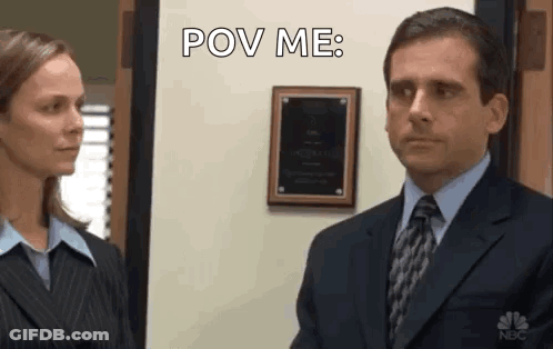 A Man In A Suit And Tie Is Looking At A Woman In A Suit And Tie . GIF