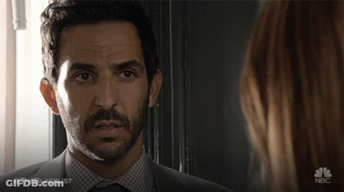 A Man In A Suit And Tie Is Looking At A Woman With The Blacklist Written On The Bottom GIF