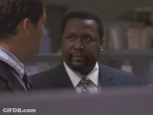 A Man In A Suit And Tie Is Looking At Another Man GIF