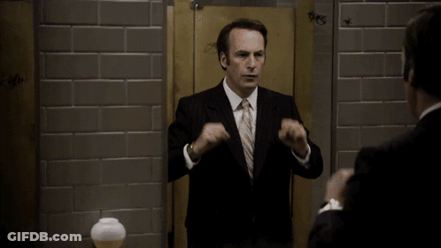 A Man In A Suit And Tie Is Looking At Himself In A Bathroom Stall With The Word Days Written On The Wall GIF