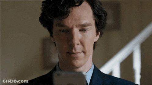 A Man In A Suit And Tie Is Looking At His Phone GIF