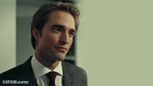 A Man In A Suit And Tie Is Looking At Something GIF