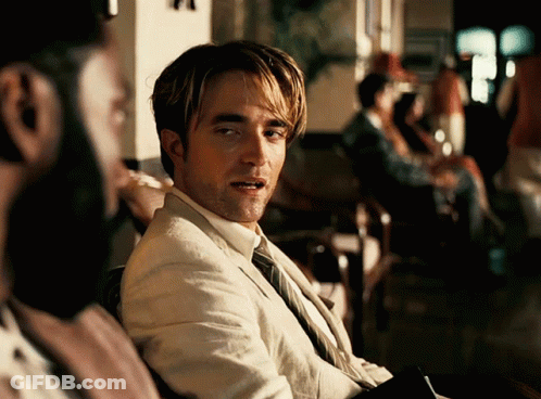 A Man In A Suit And Tie Is Looking At Something GIF