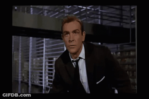 A Man In A Suit And Tie Is Looking At Something GIF