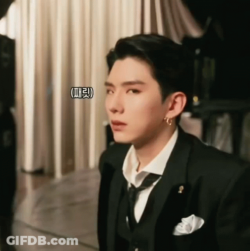 A Man In A Suit And Tie Is Looking At Something GIF