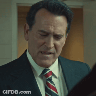 A Man In A Suit And Tie Is Looking At Something GIF