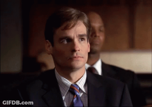 A Man In A Suit And Tie Is Looking At Something GIF