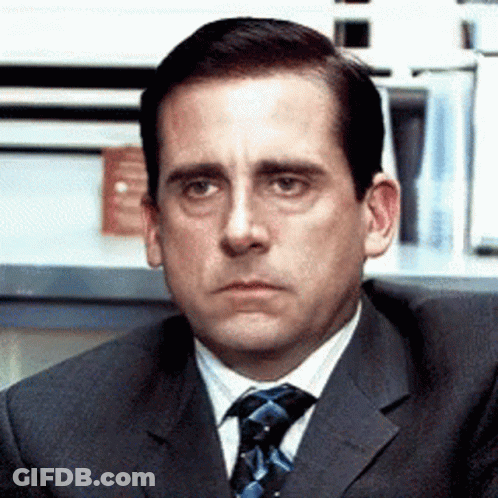 A Man In A Suit And Tie Is Looking At Something GIF