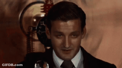 A Man In A Suit And Tie Is Looking At Something GIF