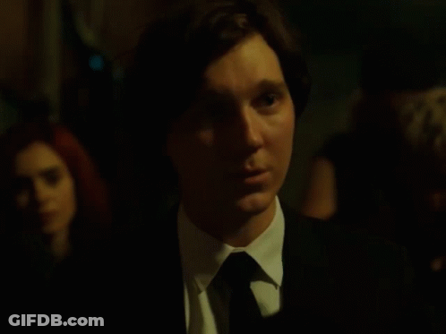 A Man In A Suit And Tie Is Looking At Something GIF