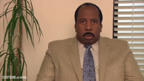 A Man In A Suit And Tie Is Looking At The Camera GIF