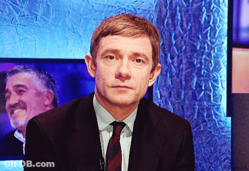 A Man In A Suit And Tie Is Looking At The Camera GIF