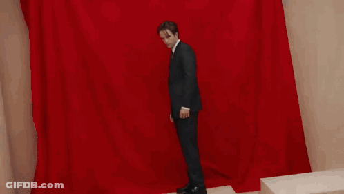 A Man In A Suit And Tie Is Looking At The Camera . GIF
