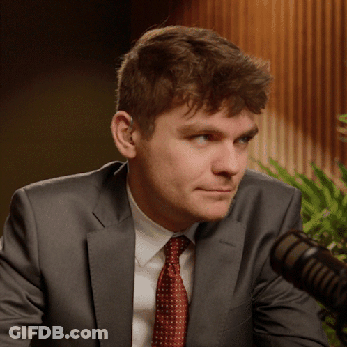 A Man In A Suit And Tie Is Looking At The Camera GIF