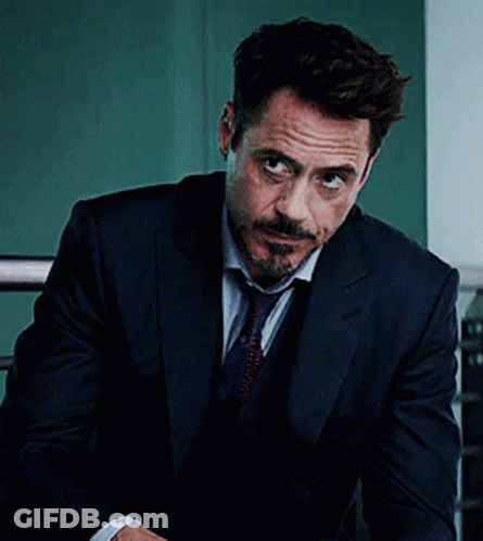 A Man In A Suit And Tie Is Looking At The Camera GIF