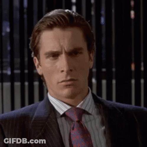 A Man In A Suit And Tie Is Looking At The Camera GIF