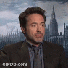 A Man In A Suit And Tie Is Looking At The Camera GIF