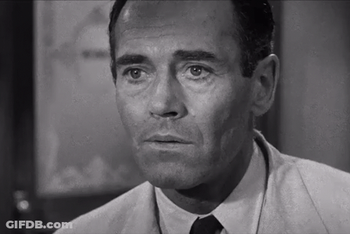 A Man In A Suit And Tie Is Looking At The Camera GIF