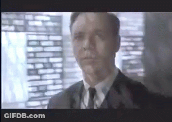 A Man In A Suit And Tie Is Looking At The Camera GIF
