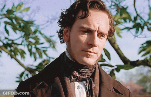 A Man In A Suit And Tie Is Looking At The Camera GIF