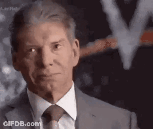 A Man In A Suit And Tie Is Looking At The Camera With A Blurred Background . GIF