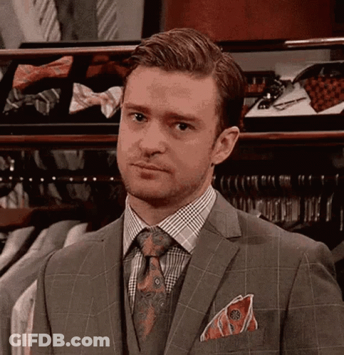 A Man In A Suit And Tie Is Looking At The Camera . GIF