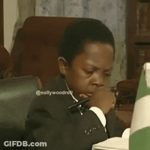 A Man In A Suit And Tie Is Looking Down At Something .. GIF