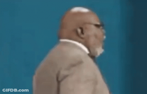 A Man In A Suit And Tie Is Looking Down At Something . GIF