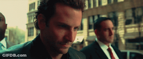 A Man In A Suit And Tie Is Looking Down At Something GIF