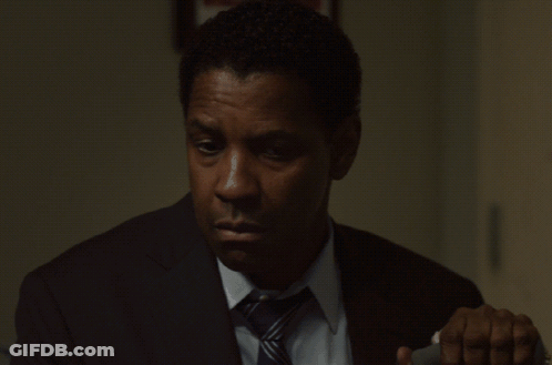 A Man In A Suit And Tie Is Looking Down At Something GIF