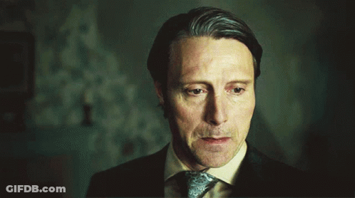 A Man In A Suit And Tie Is Looking Down With His Eyes Closed GIF