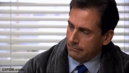 A Man In A Suit And Tie Is Looking Down GIF