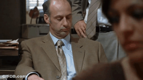 A Man In A Suit And Tie Is Looking Down GIF