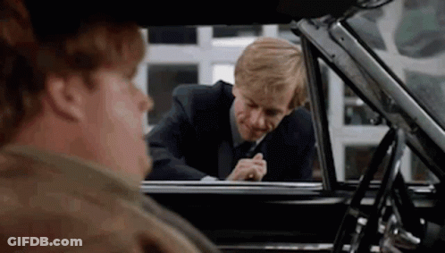A Man In A Suit And Tie Is Looking Out The Window Of A Car . GIF