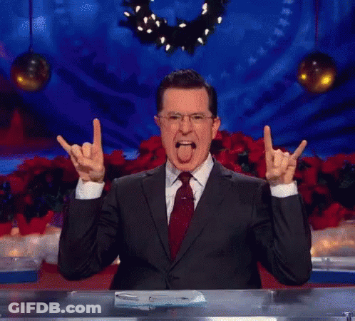 A Man In A Suit And Tie Is Making A Devil Horns Sign With His Hands GIF