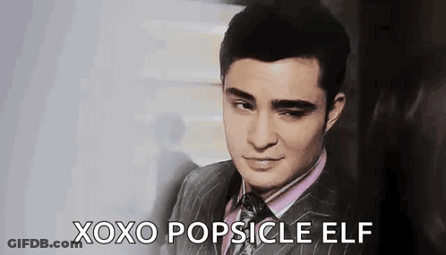 A Man In A Suit And Tie Is Making A Face And Saying `` Xoxo Popsicle Elf '' . GIF