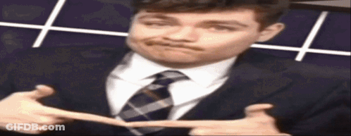 A Man In A Suit And Tie Is Making A Face GIF