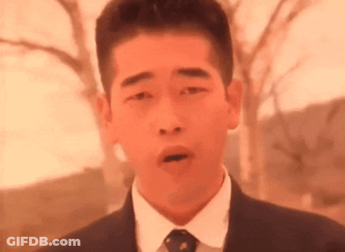 A Man In A Suit And Tie Is Making A Face With His Mouth Open . GIF