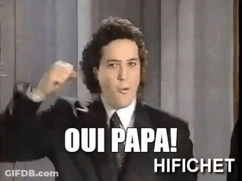 A Man In A Suit And Tie Is Making A Fist In The Air And Says Oui Papa ! GIF