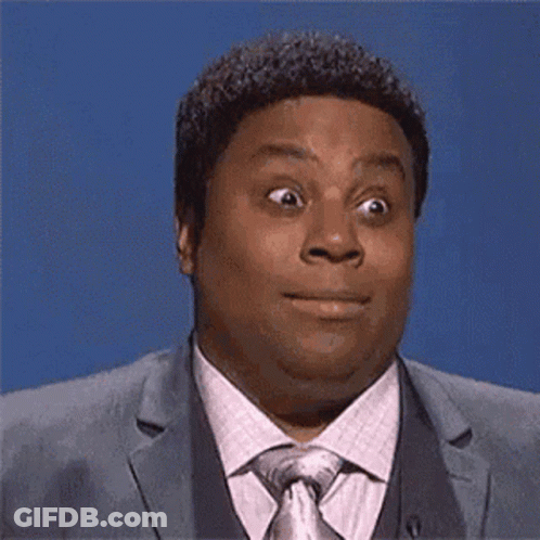 A Man In A Suit And Tie Is Making A Funny Face And Looking At The Camera . GIF