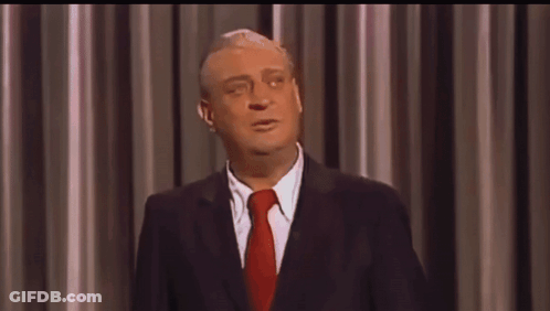 A Man In A Suit And Tie Is Making A Funny Face GIF