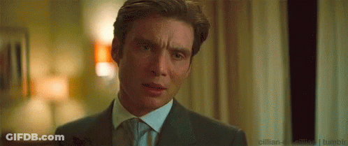 A Man In A Suit And Tie Is Making A Funny Face In A Room . GIF