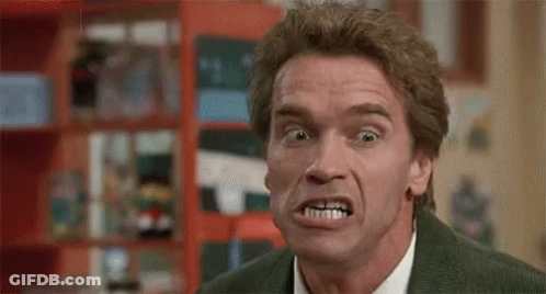 A Man In A Suit And Tie Is Making A Funny Face In A Room . GIF