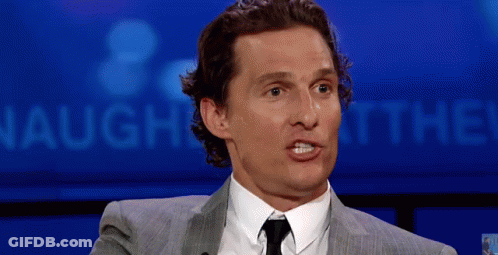 A Man In A Suit And Tie Is Making A Funny Face In Front Of A Sign That Says Laugh At The ! GIF