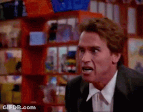 A Man In A Suit And Tie Is Making A Funny Face In Front Of A Toy Store . GIF