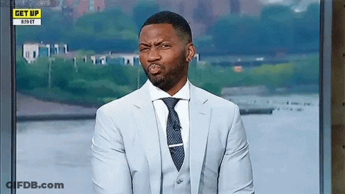 A Man In A Suit And Tie Is Making A Funny Face On A Television Show . GIF